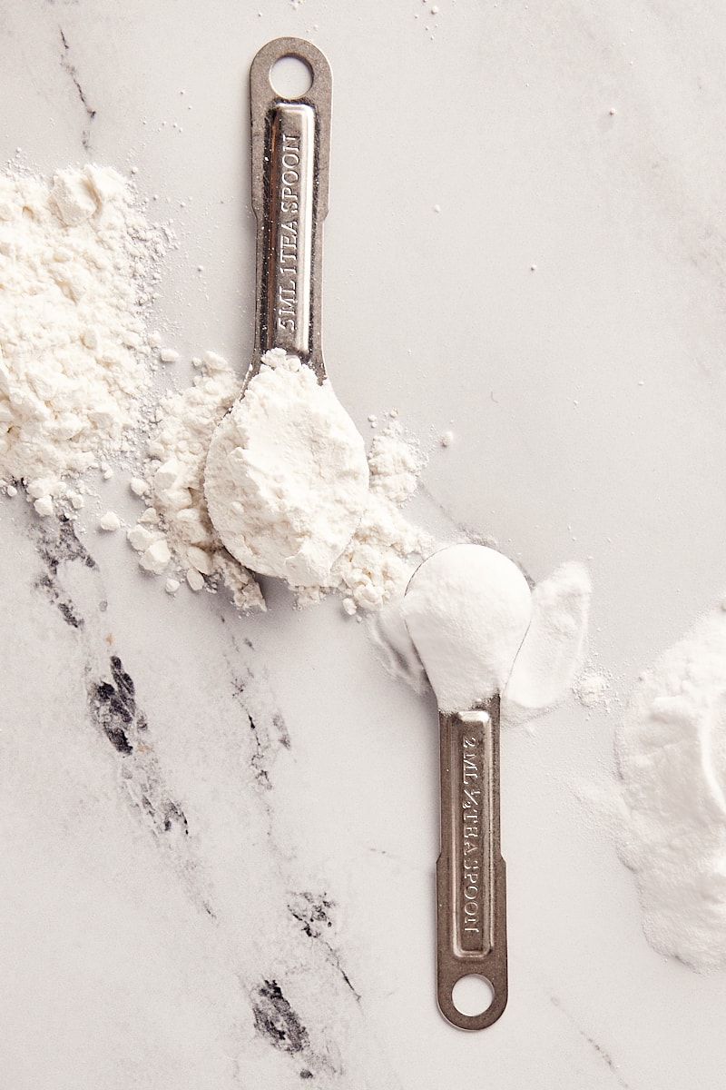 overhead view of baking powder and baking soda in measuring spoons