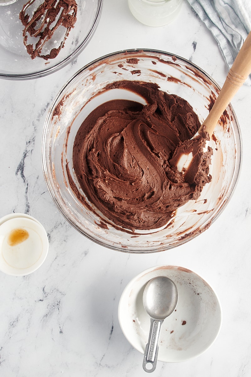 overhead view of chocolate buttercream frosting in a glass mixing bowl
