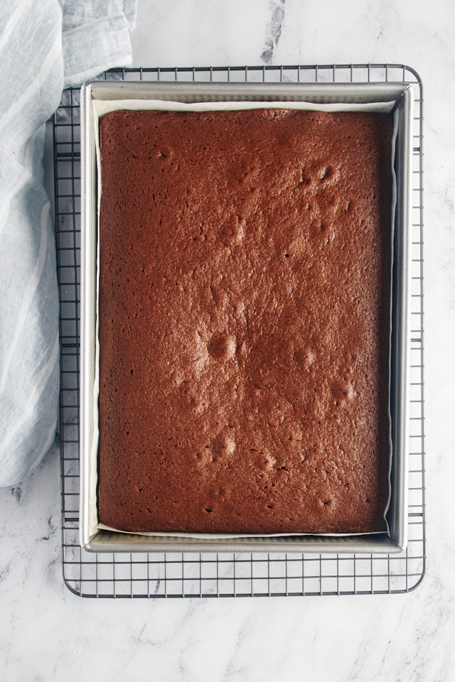 overhead view of freshly baked chocolate sheet cake in a 9x13 pan on a wire rack
