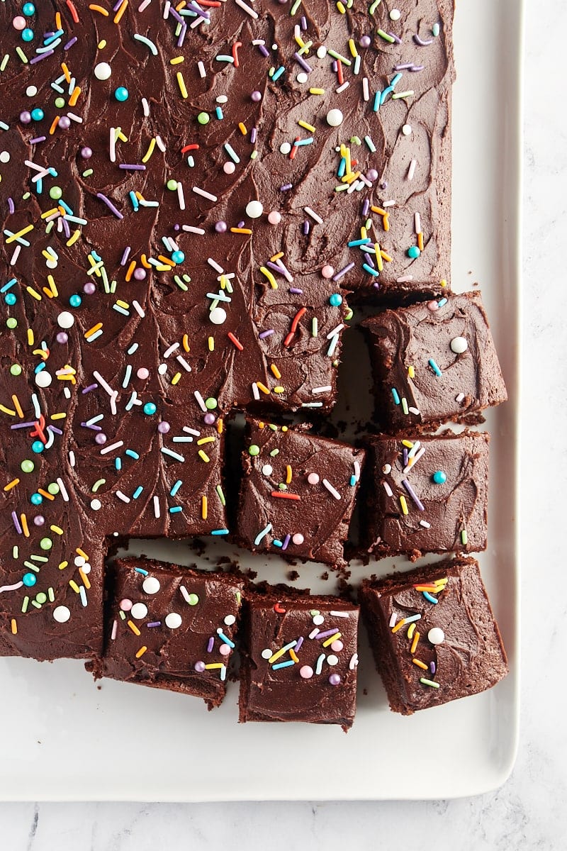 overhead view of partially sliced Chocolate Sheet Cake on a white serving tray