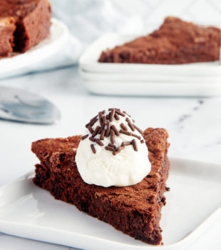 Slice of brownie cake on plate with whipped cream and sprinkles