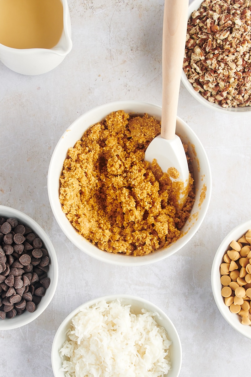 Overhead view of graham crust mixture in small bowl with rubber spatula