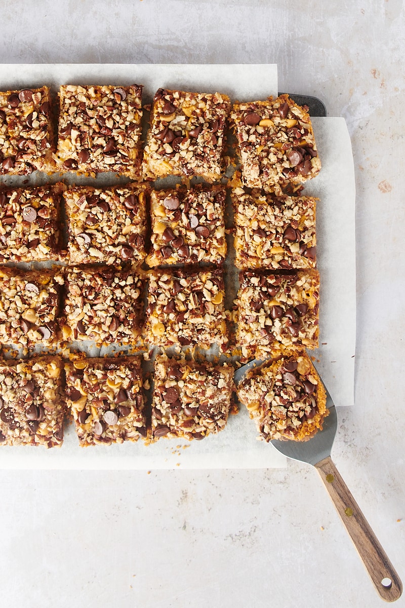 Seven layer bars on parchment paper with spatula