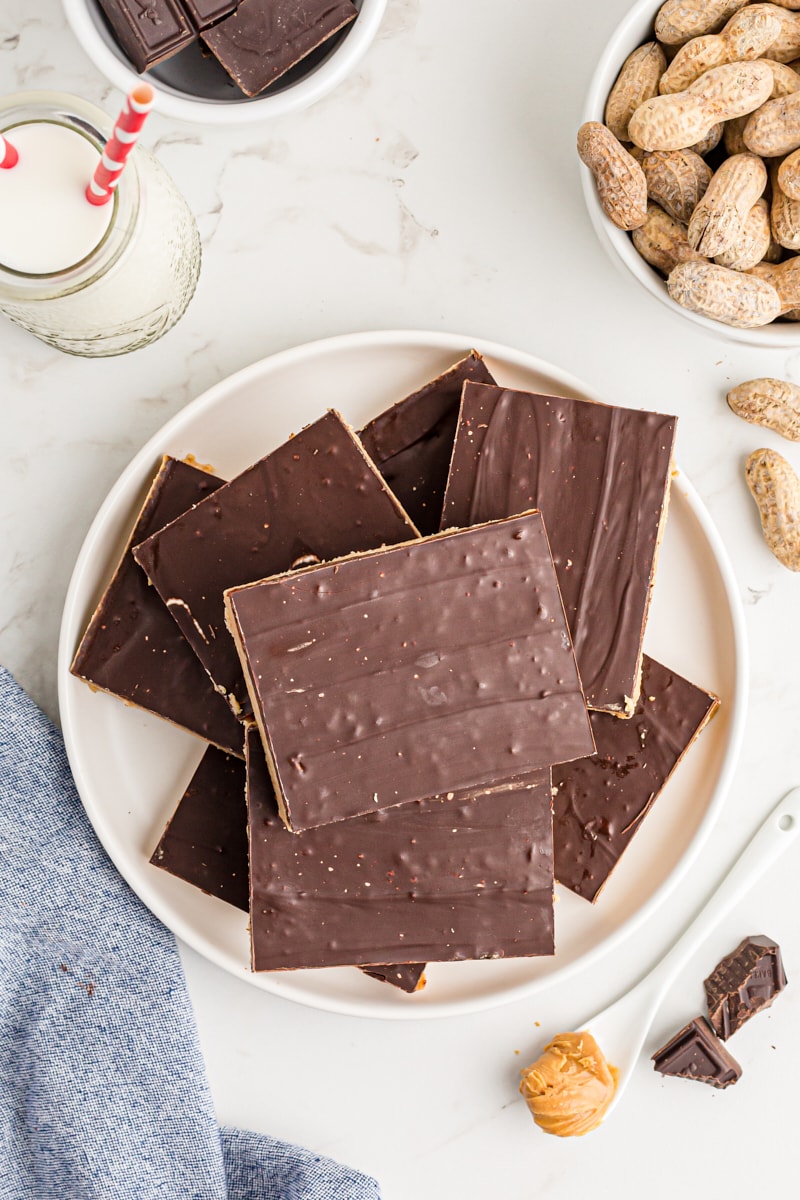 Overhead view of assorted no-bake peanut butter bars stacked on plate.