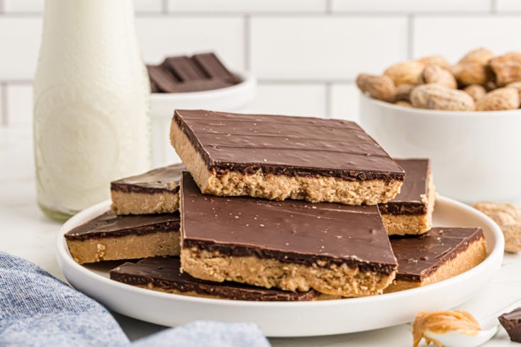 Stacked no-bake peanut butter chocolate bars on white plate