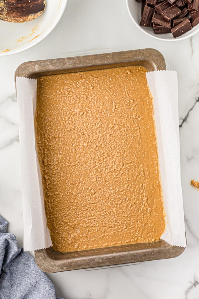 Overhead view of the peanut butter layer in a parchment-lined pan.