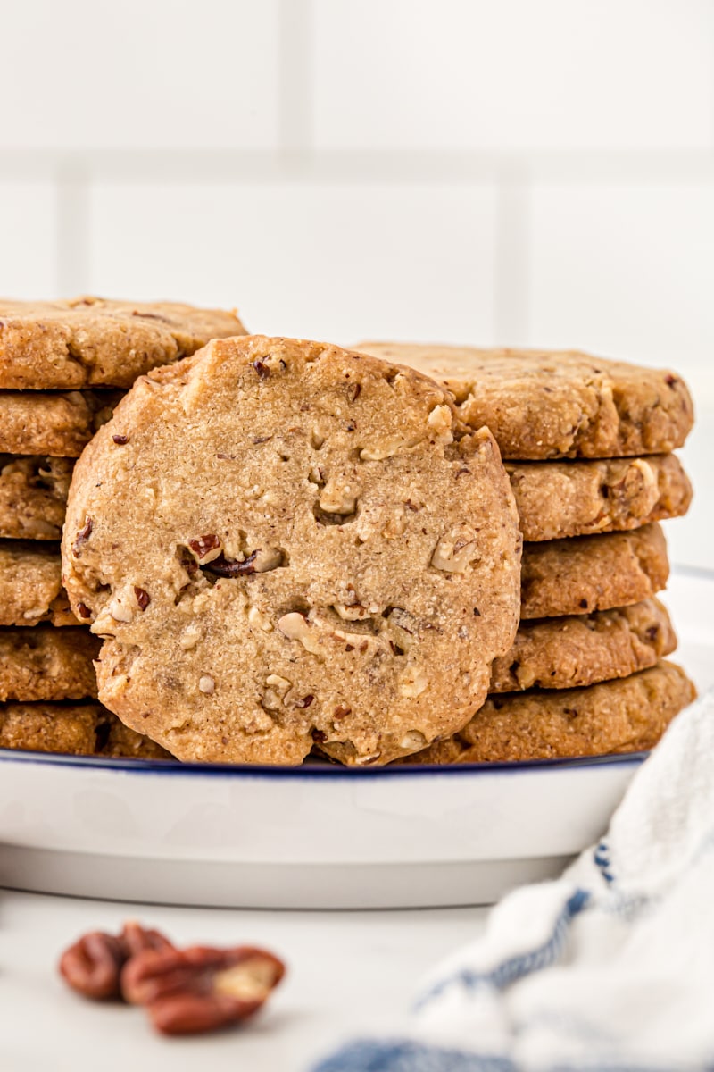 Stacks of pecan sandies on a plate, with one cookie on its side.