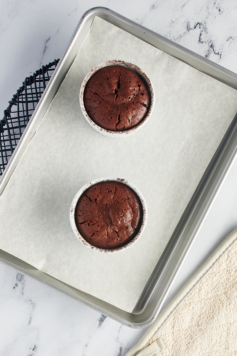 overhead view of freshly baked Flourless Chocolate Cakes for Two on a parchment-lined sheet pan