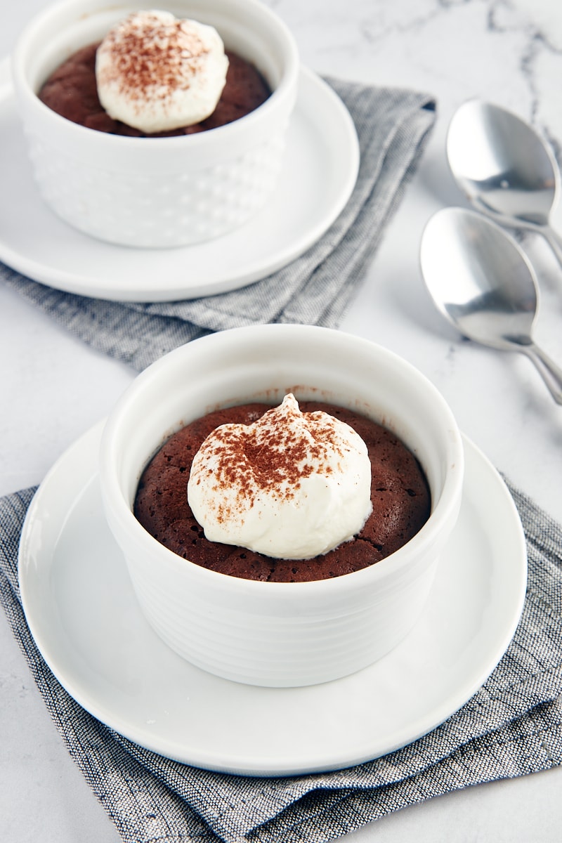 Flourless Chocolate Cakes for Two served in white ramekins and topped with whipped cream and cocoa powder