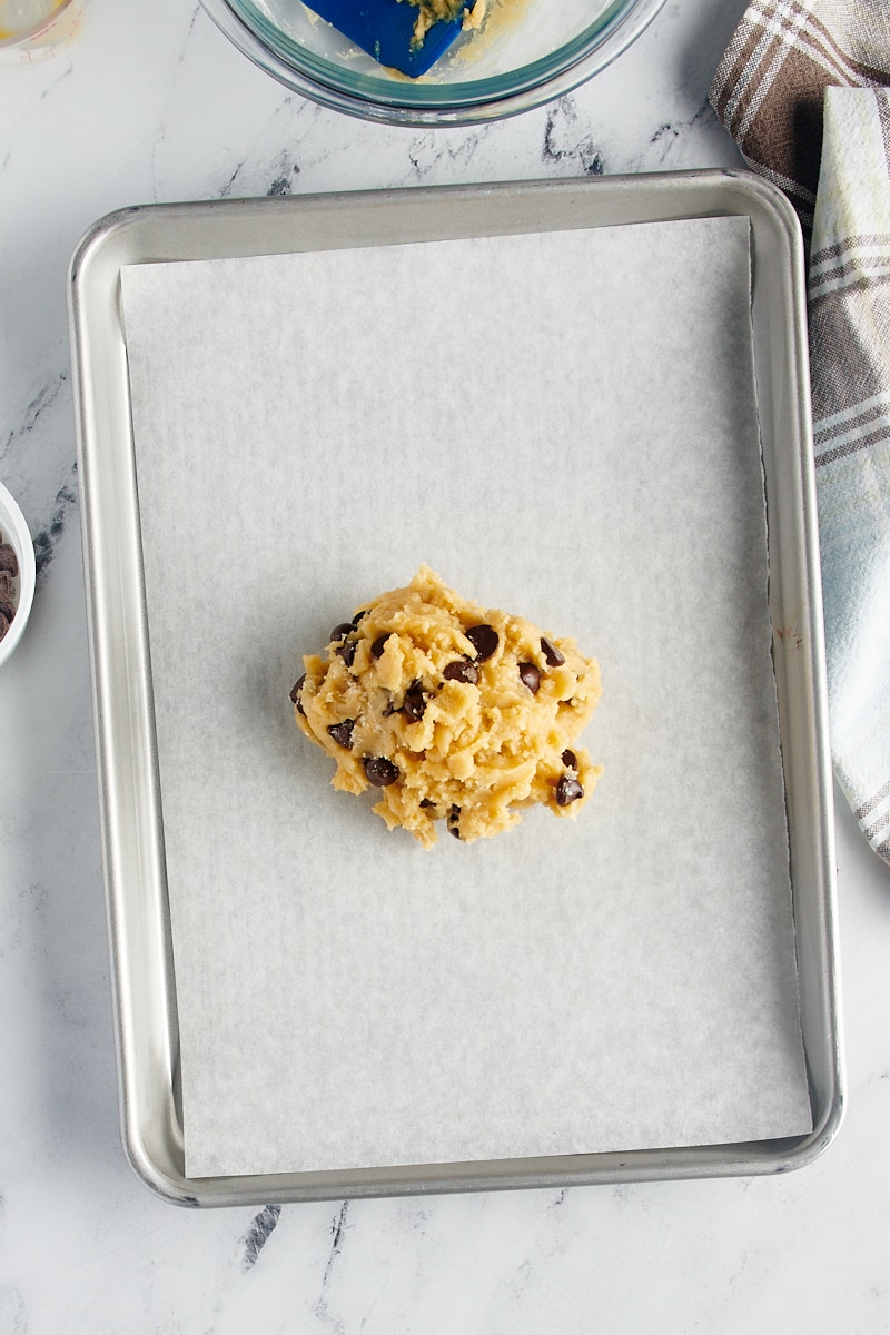 overhead view of chocolate chip cookie dough on a parchment-lined baking sheet
