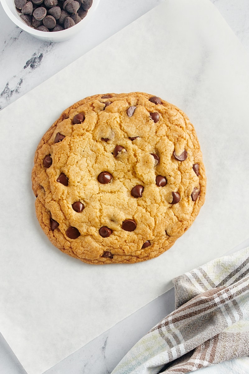 overhead view of a giant chocolate chip cookie on parchment paper