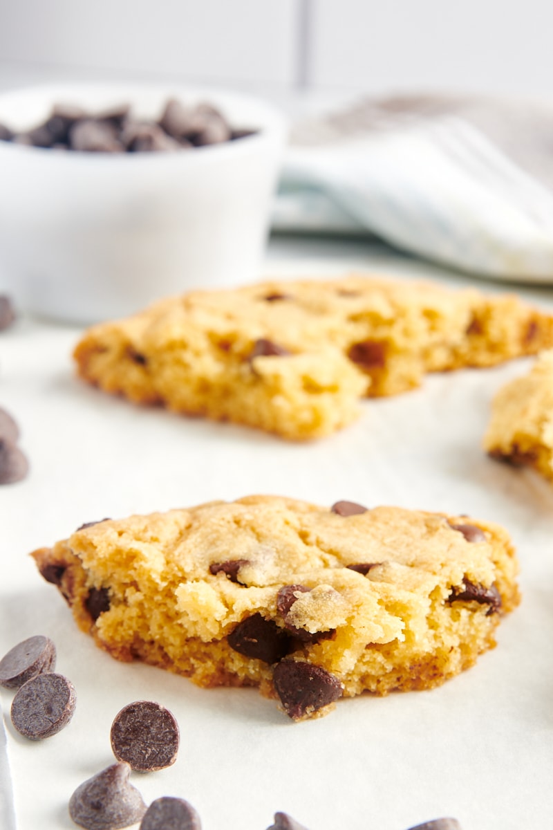 pieces of a giant chocolate chip cookie on white parchment paper