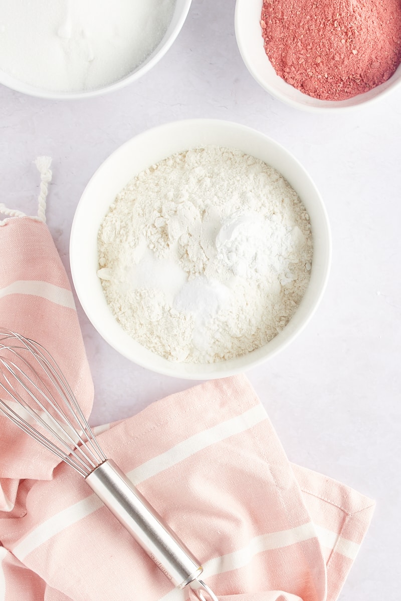 overhead view of flour, baking powder, baking soda, and salt in a white mixing bowl