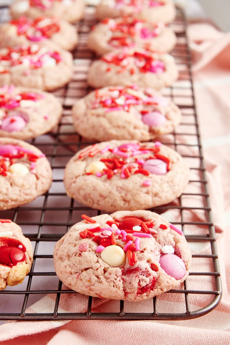 Strawberry M&M Cookies lined up on a wire rack