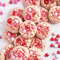 overhead view of Strawberry M&M Cookies on a marble surface with red, pink, and white M&Ms scattered around the cookies