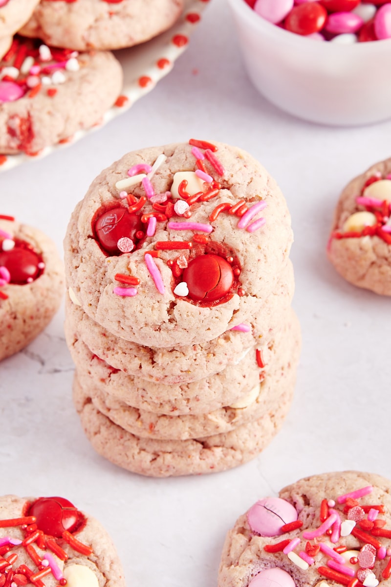 stack of five Strawberry M&M Cookies surrounded by more cookies