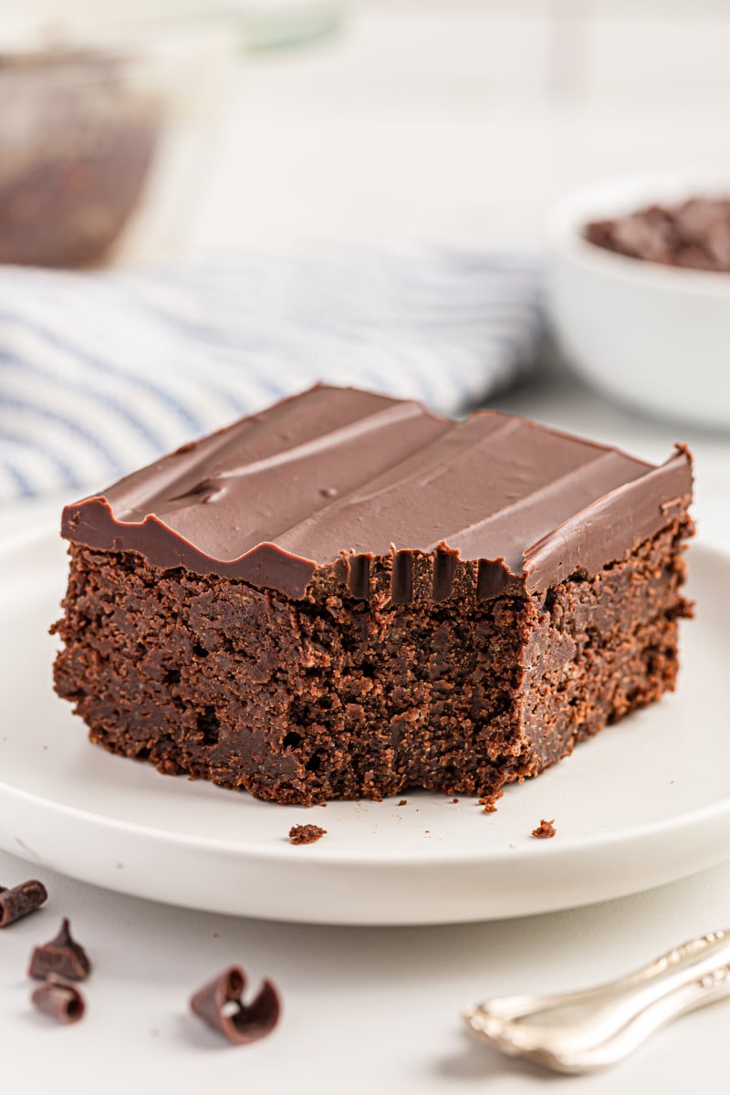 Chocolate mascarpone brownie on white plate with corner eaten