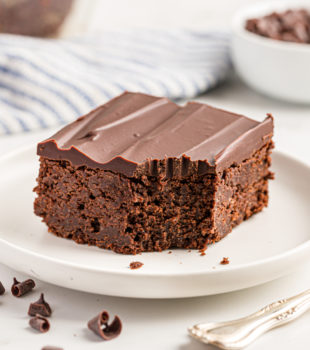 Chocolate mascarpone brownie on white plate with corner eaten