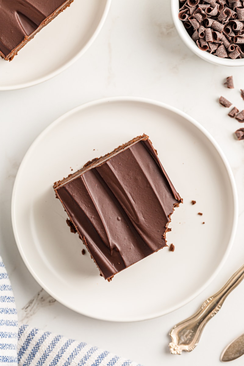 Overhead view of chocolate mascarpone brownie on white plate with corner eaten