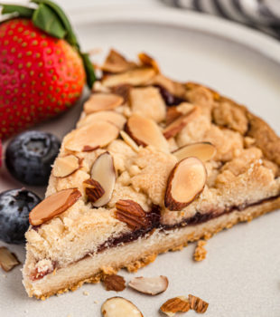 slice of Italian Jam Crostata on a white plate with fresh berries