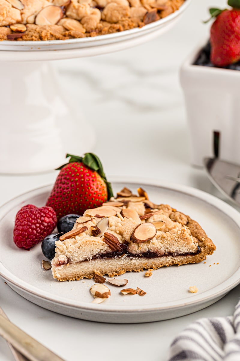 slice of Italian Jam Crostata served with fresh berries on a white plate