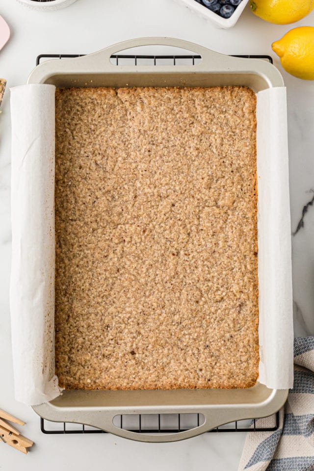 Overhead view of baked pecan crust in parchment-lined pan