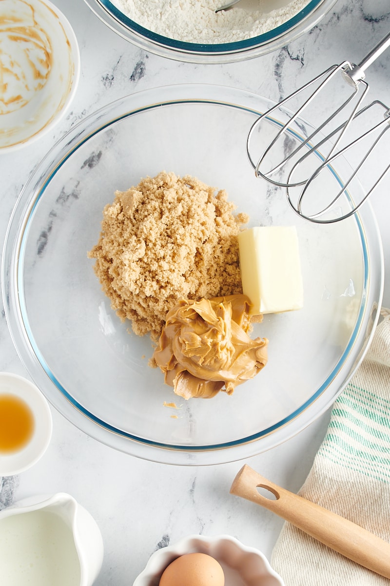 Overhead view of brown sugar, butter, and peanut butter in glass mixing bowl