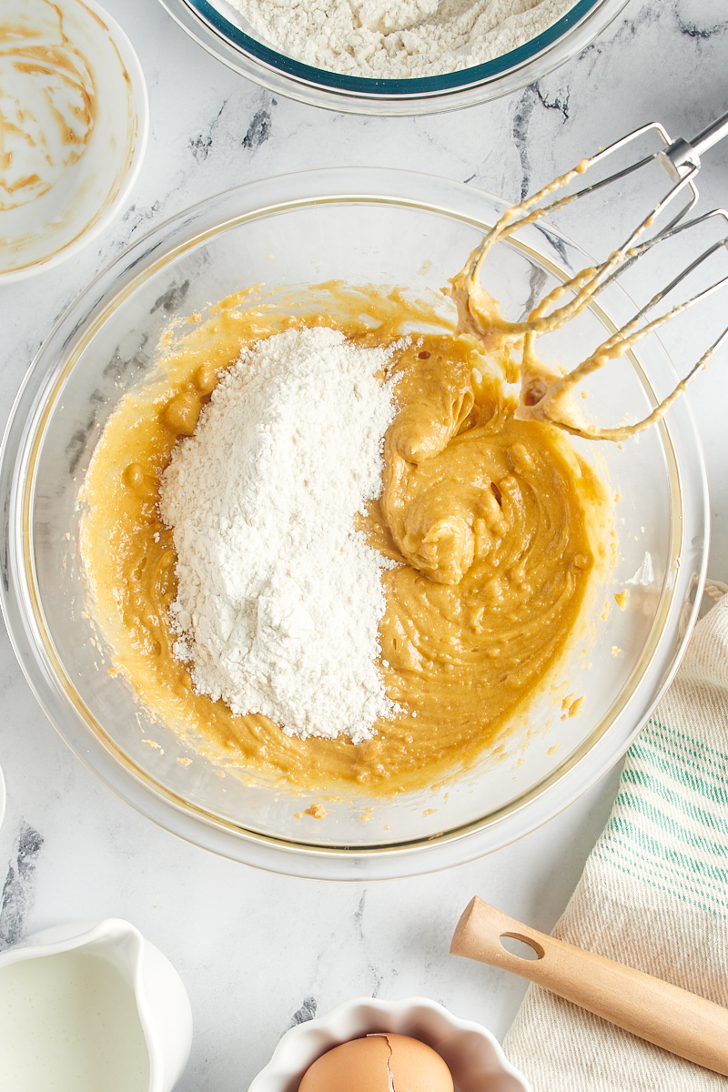 Overhead view of dry ingredients added to batter in mixing bowl