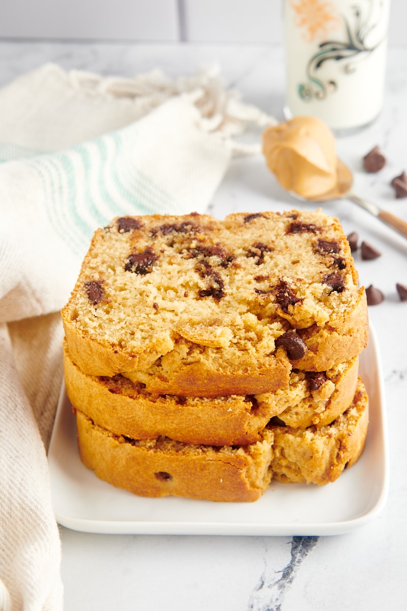 Stack of 3 slices of chocolate chip peanut butter bread on white square plate