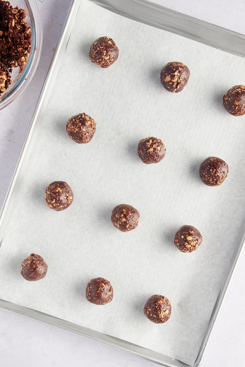 Overhead view of chocolate peanut butter granola cookies on parchment-lined baking sheet before flattening