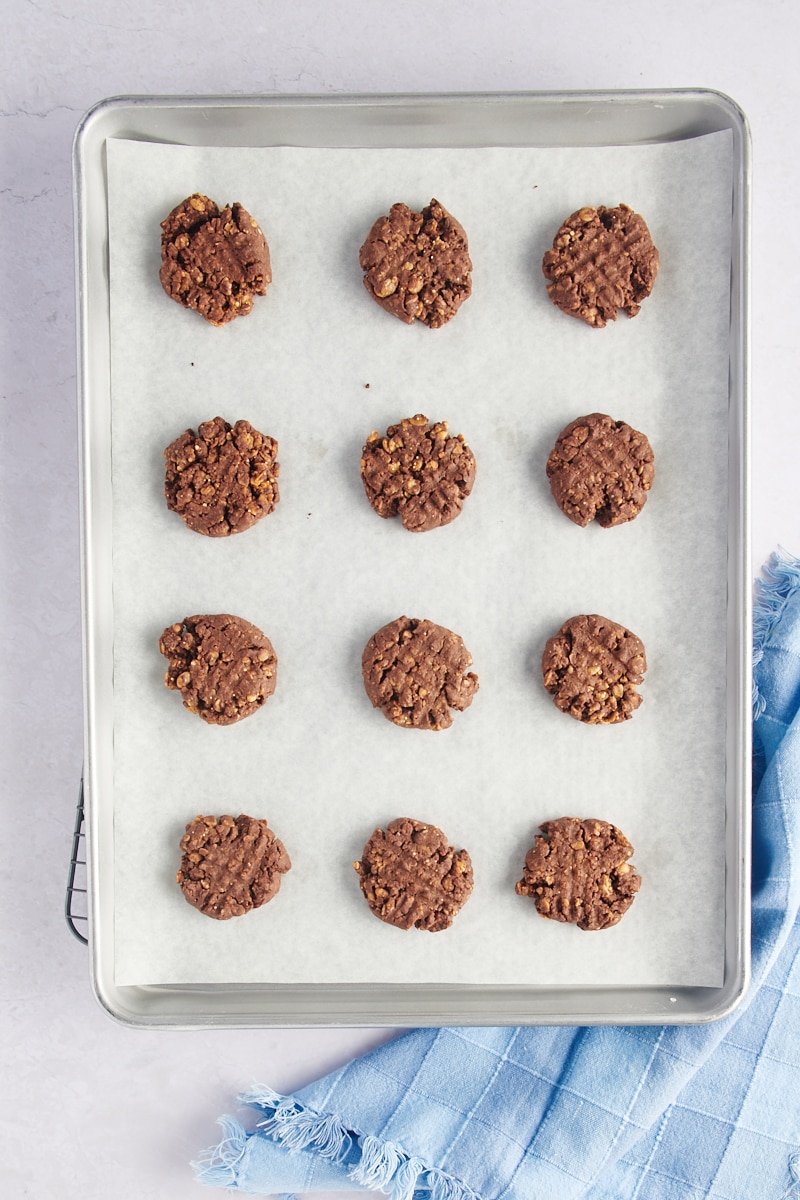 Overhead view of chocolate peanut butter granola cookies on parchment-lined baking sheet