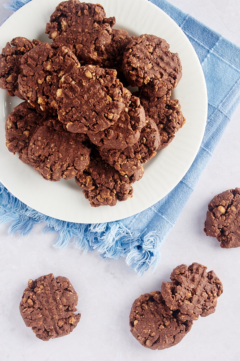 Overhead view of chocolate peanut butter granola cookies on plate and tabletop