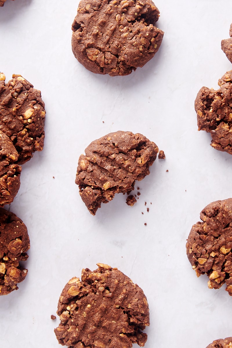 Overhead view of granola cookies on parchment paper, with bite taken out of center cookie