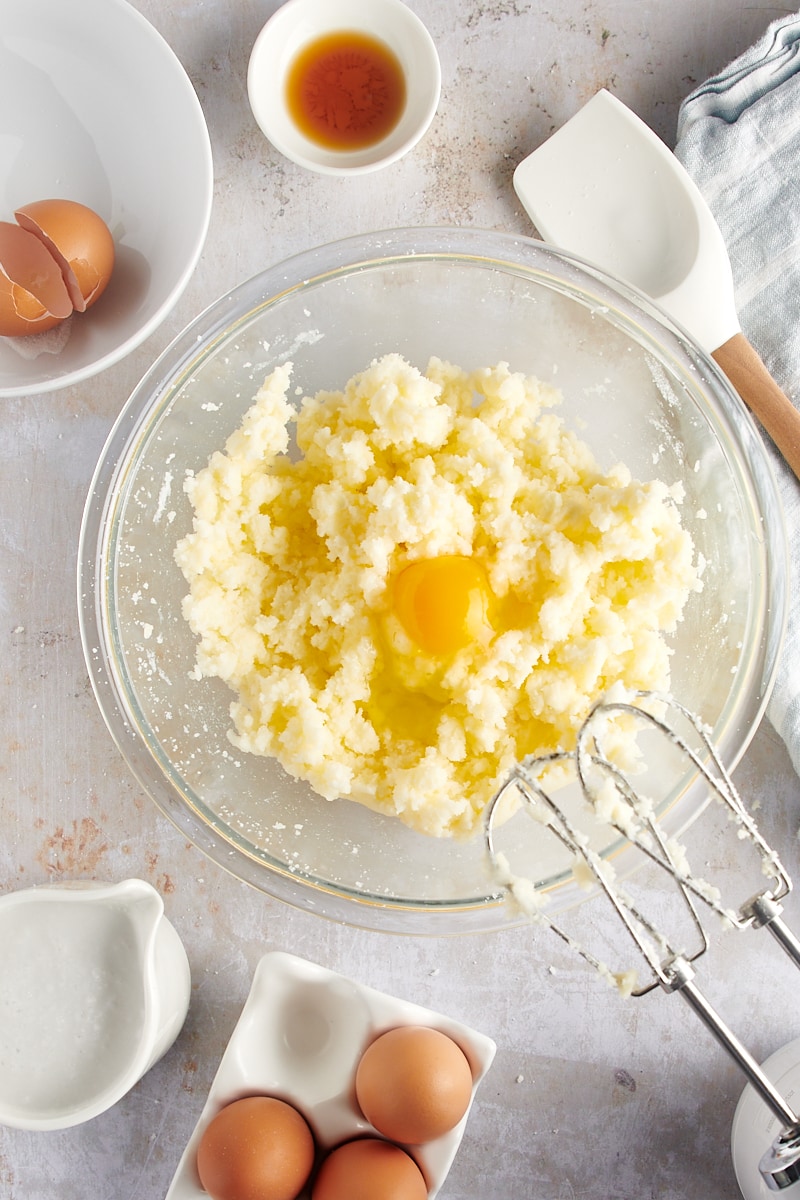 overhead view of egg added to creamed butter and sugar in a glass mixing bowl