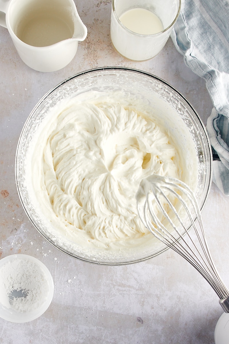 overhead view of whipped cream in a glass mixing bowl