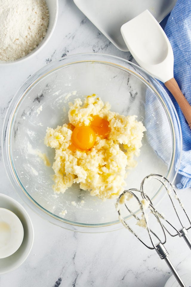 overhead view of egg yolks and vanilla extract added to creamed butter and sugar in a glass mixing bowl