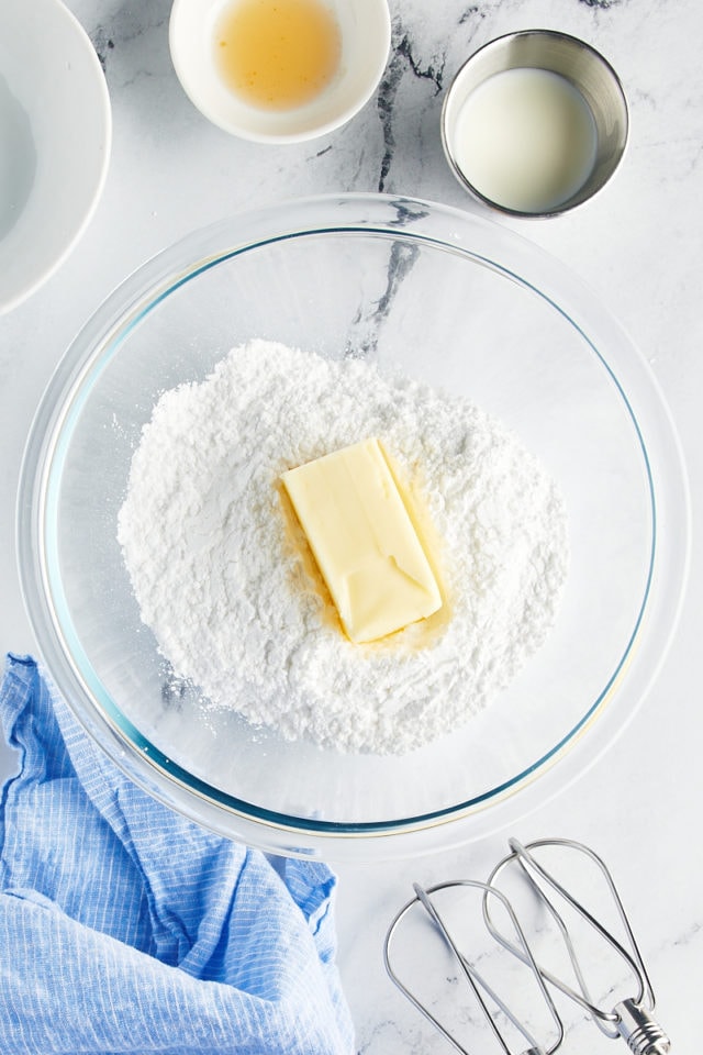 overhead view of butter and confectioners' sugar in a glass mixing bowl