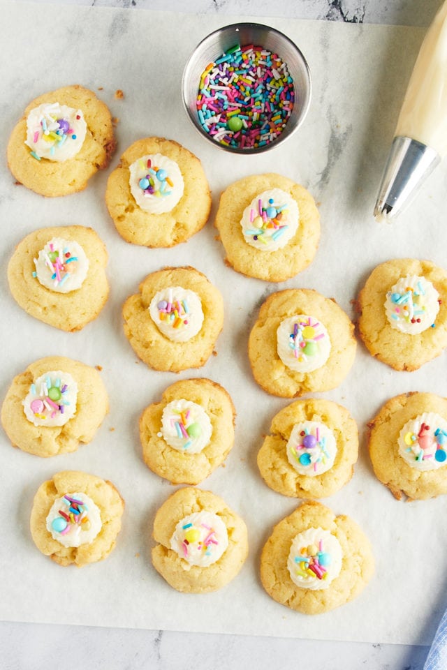 overhead view of Frosting-Filled Thumbprint Cookies on a sheet of white parchment paper