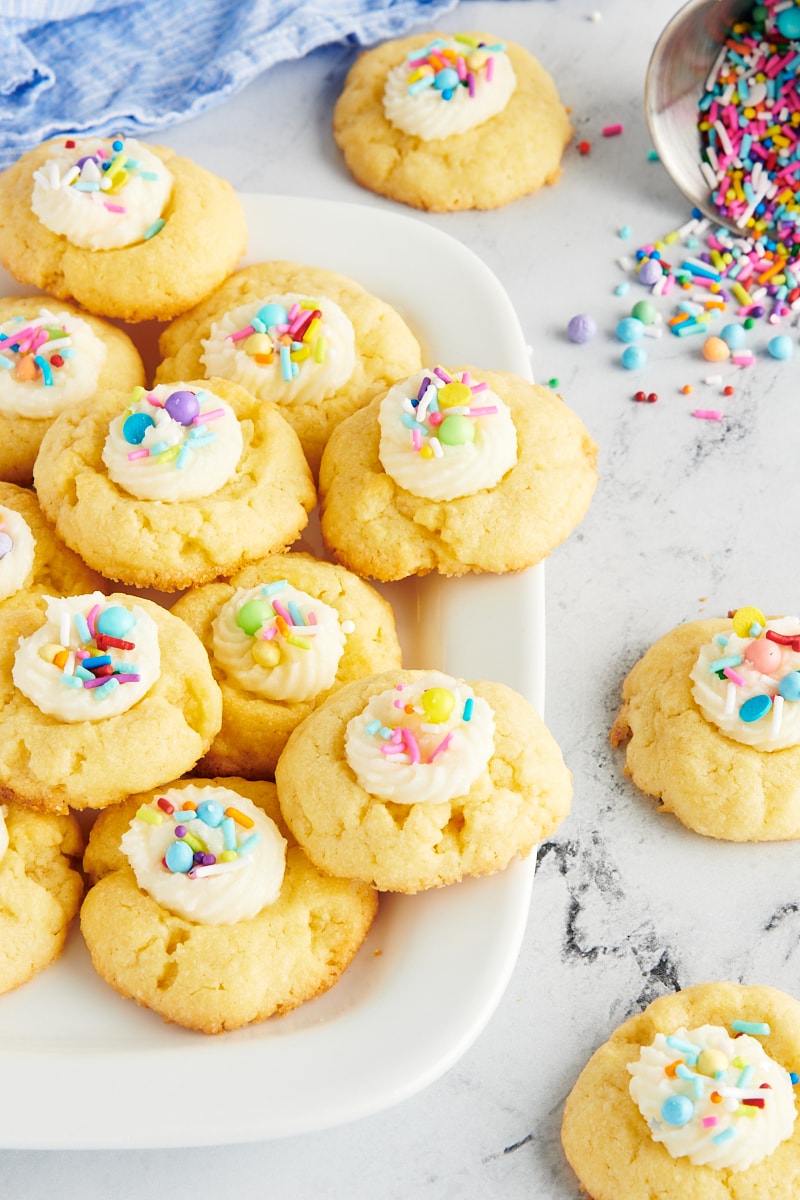 Frosting-Filled Thumbprint Cookies on a white tray and scattered on a marble surface