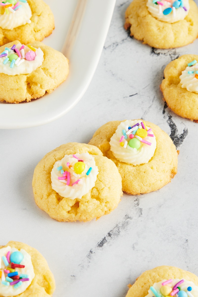 Frosting-Filled Thumbprint Cookies scattered on a marble surface and on a white plate