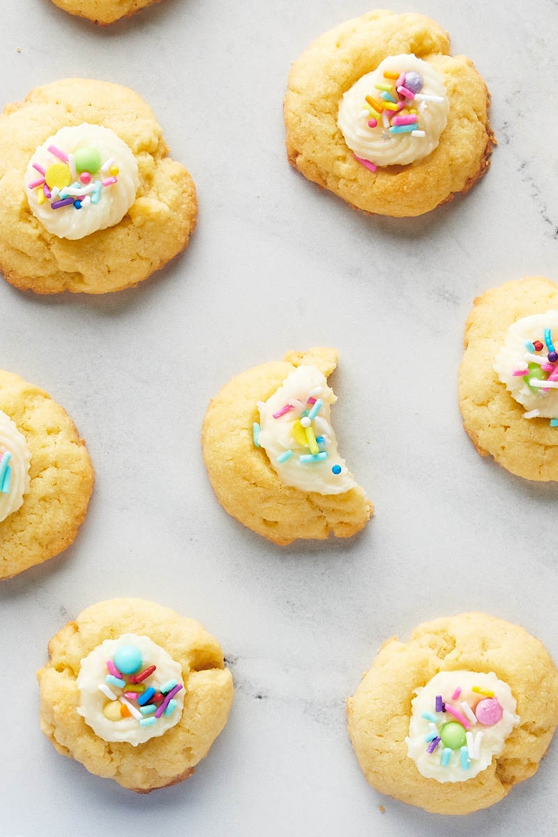 overhead view of a partial Frosting-Filled Thumbprint Cookies surrounded by more cookies on a marble surface