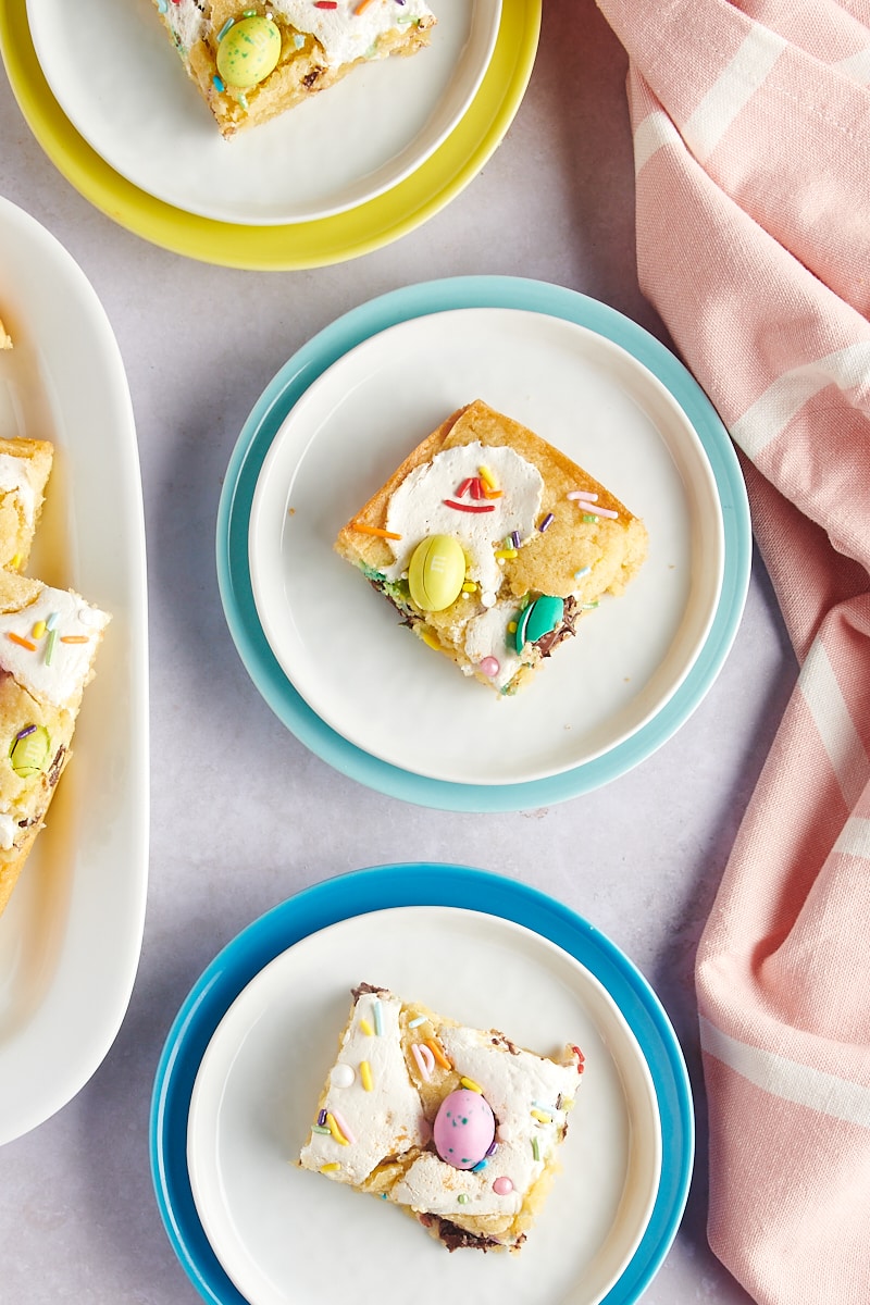 overhead view of M&M Marshmallow Sugar Cookie Bars on white plates rimmed in bright colors
