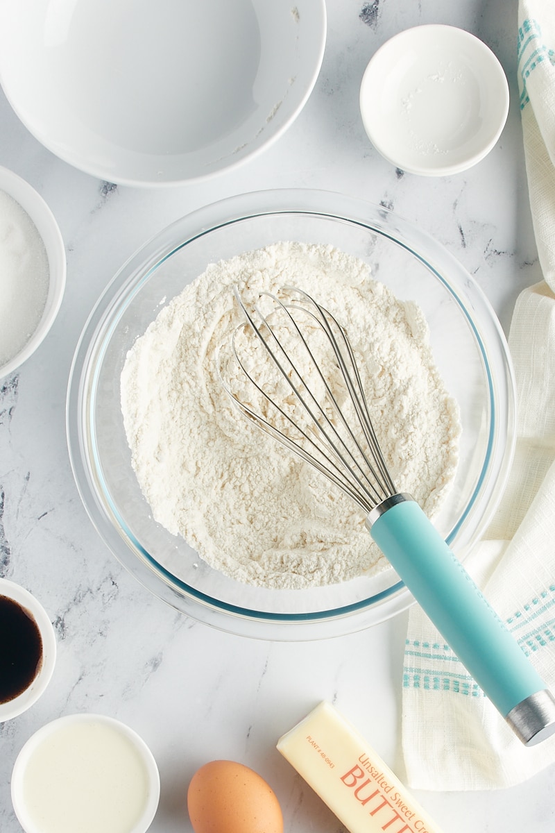 Overhead view of dry cookie ingredients with a whisk in a mixing bowl.
