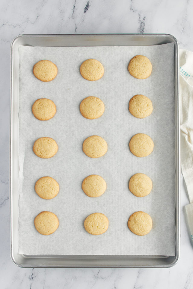Overhead view of vanilla wafer cookies on a parchment-lined baking sheet.