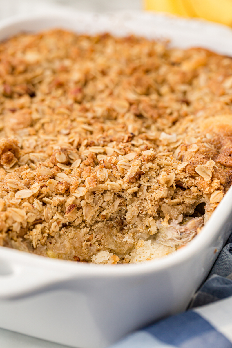 Banana bread cobbler in white baking dish with scoop removed