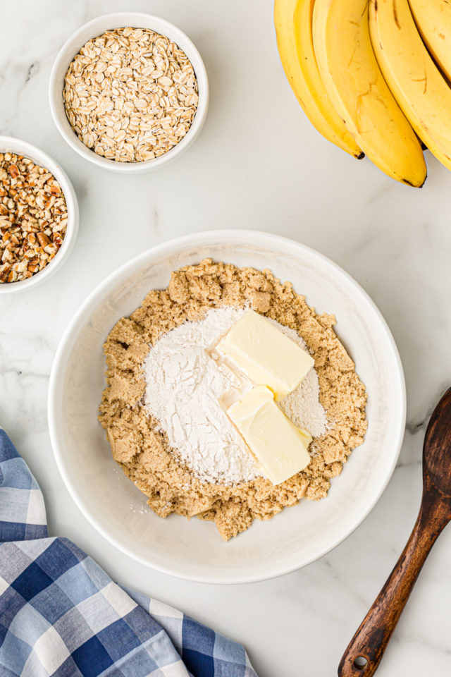 Overhead view of butter and flour added to brown sugar in mixing bowl