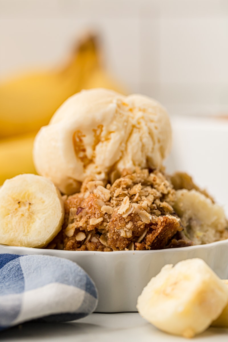 Banana bread cobbler in dish with banana slices and vanilla ice cream