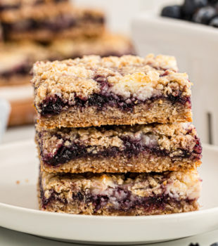 Stack of 3 blueberry jam cream cheese bars on white plate