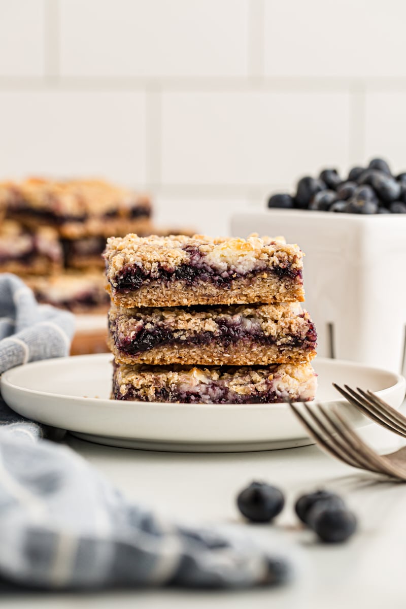 Stack of 3 blueberry jam cream cheese bars on white plate