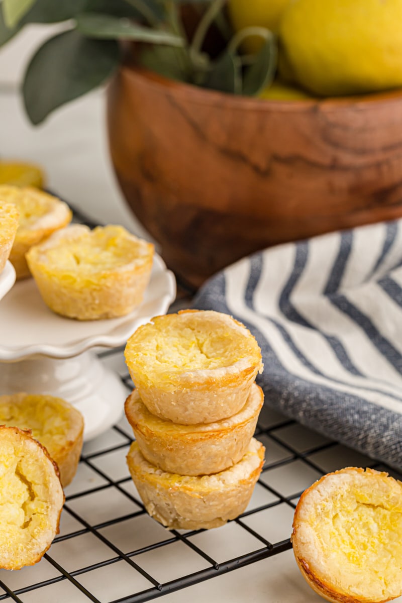 a stack of three Lemon Chess Tartlets on a wire rack, surrounded by more tarts